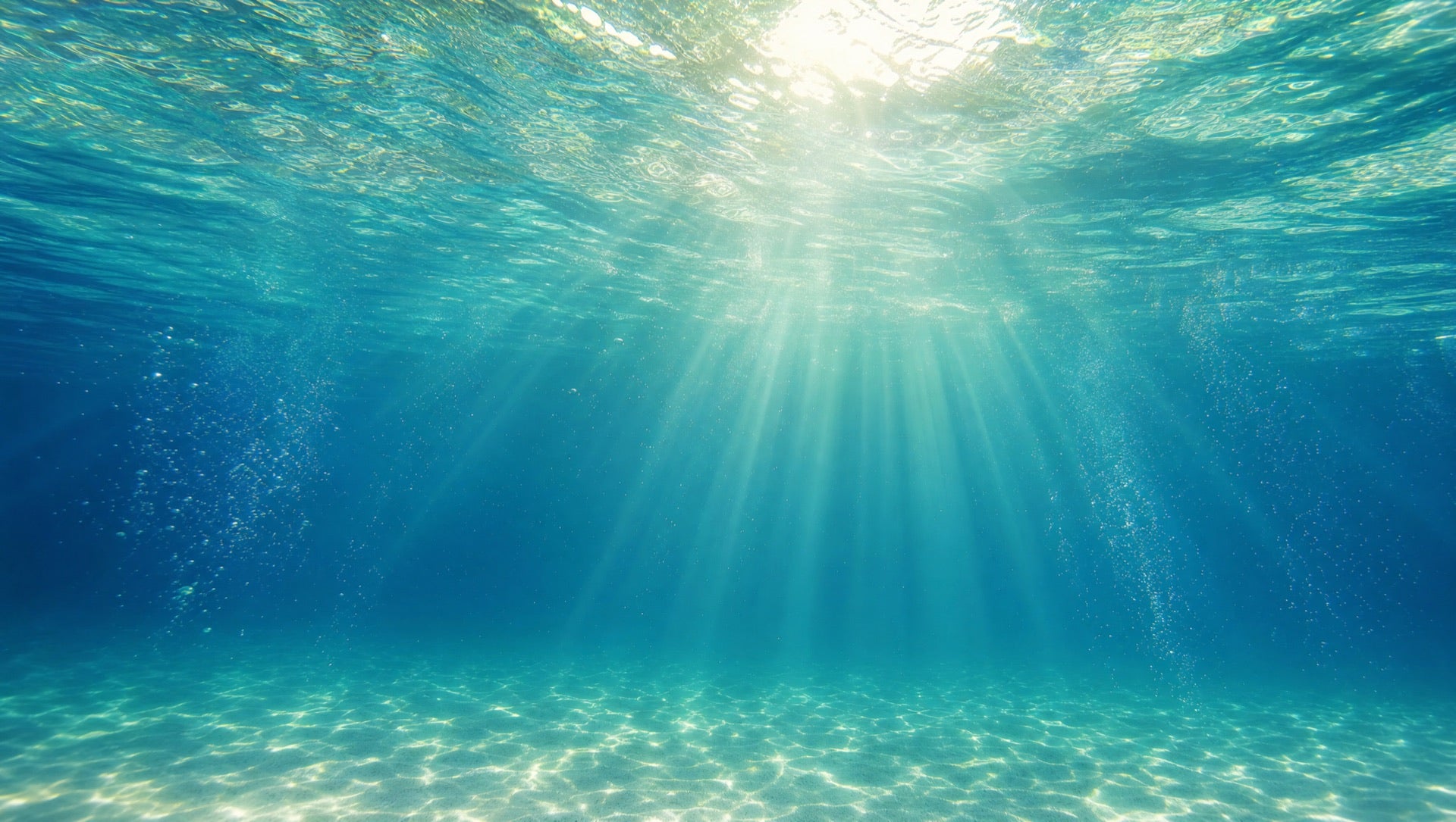 Looking up through turquoise water at sun rays breaking the surface