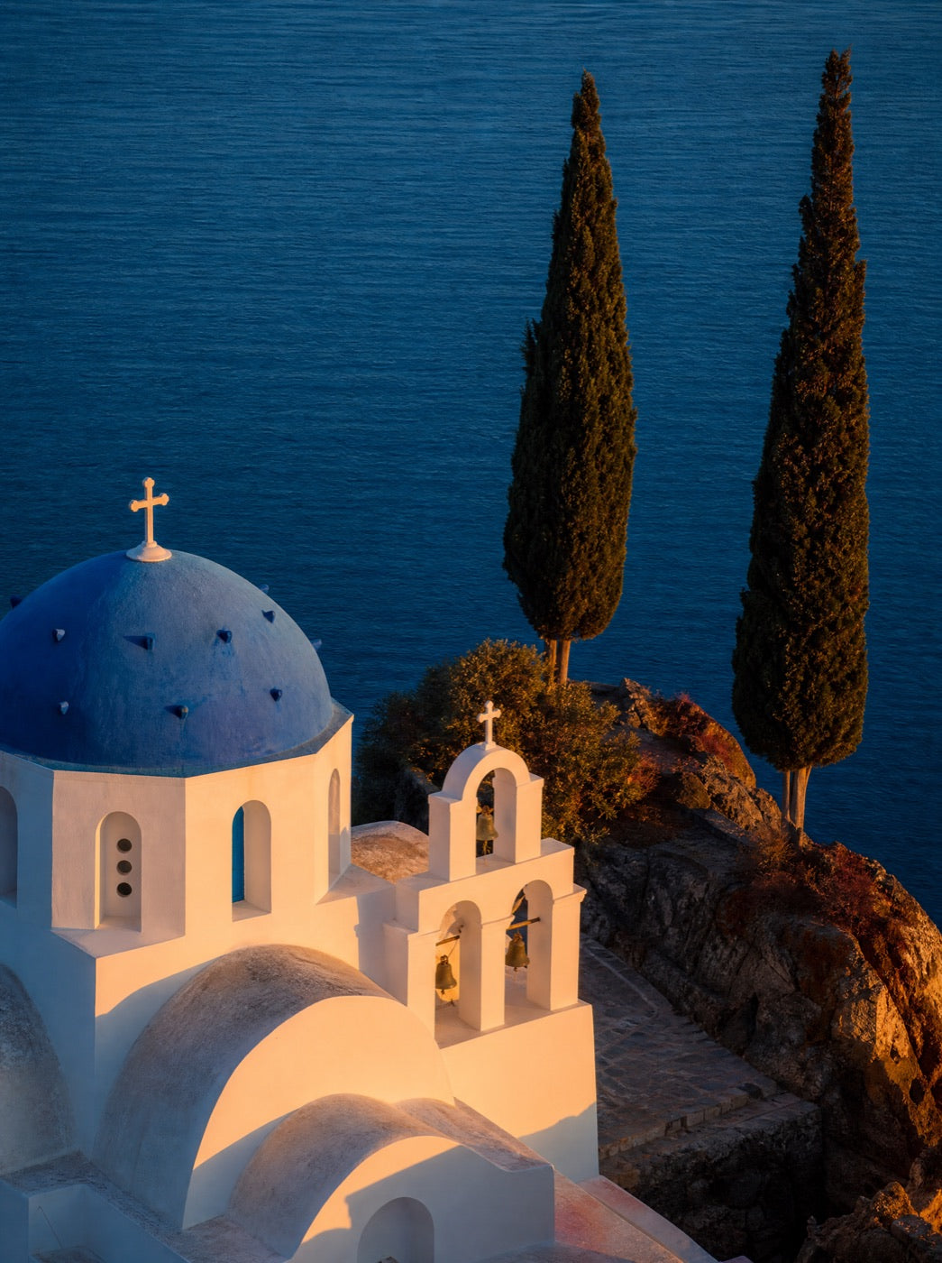 A white chapel and cypress against the evening sea
